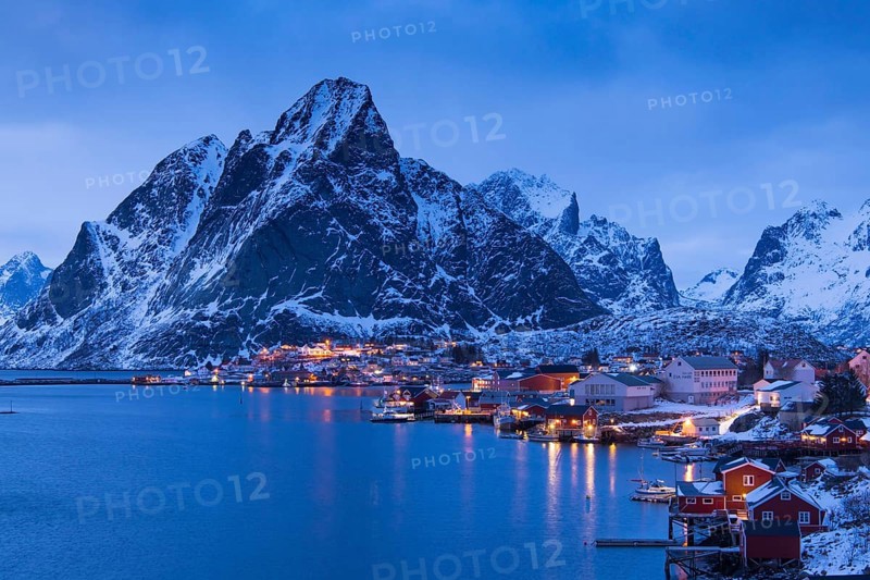 Fishermen's Village in front of snowy mountain range at the coastline in winter, Lofoten, Norway