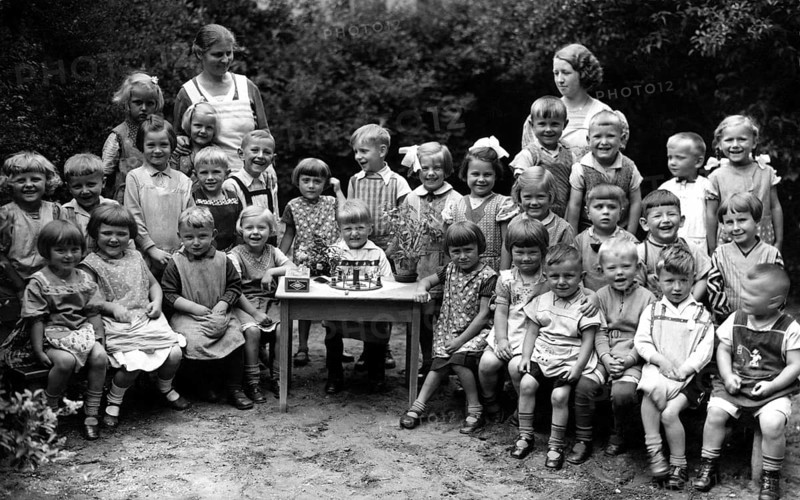 School class, 1900, A group of children with teachers posing happily outdoors for a black and white photo, Historical photo