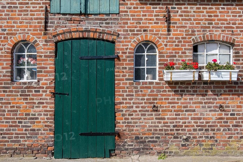Nostalgic brick wall with green door and white windows, decorated with flower pots, Föhr, Nordfriesland, Schleswig-Holstein, Germany
