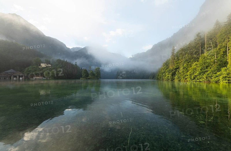 Mystical morning at Königssee in Schönau with boathouses and Christlieger. Sunrise and beautiful wafts of mist over the Königssee in the basin