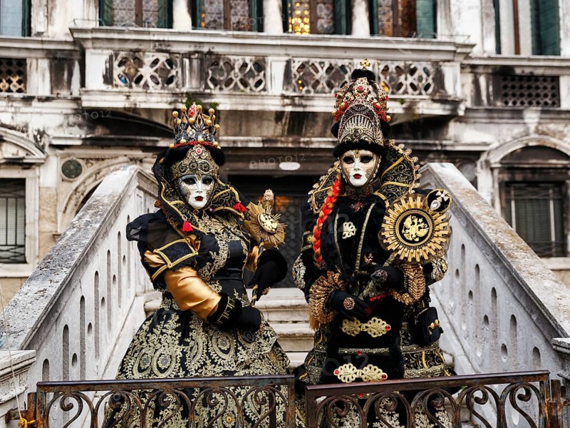 Two people in costume posing on a staircase, Venetian costumes with masks, Carnival in Venice, Italy