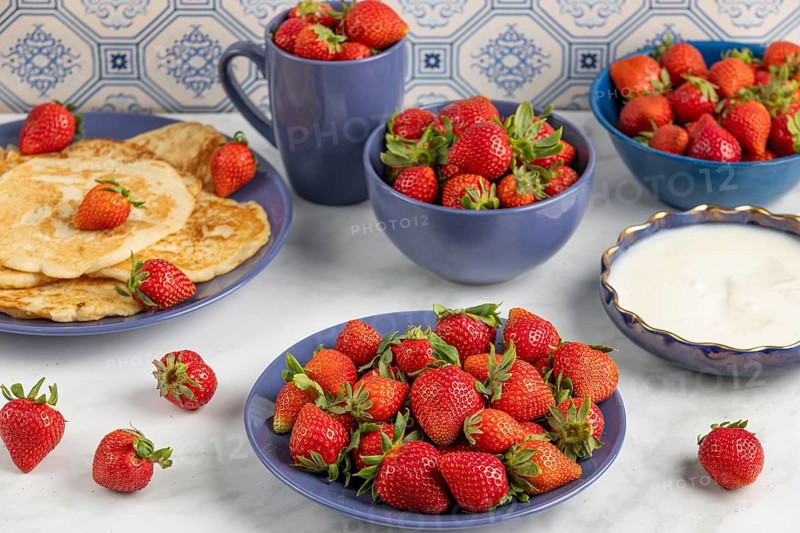 An appetising display of strawberries and pancakes on a table with blue crockery