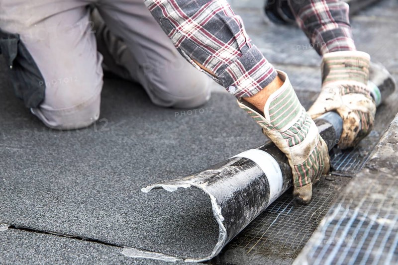 Roofers during waterproofing work with bitumen membranes