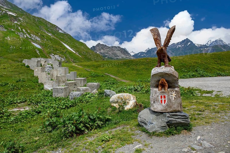 Historical border fortification from the Second World War WW II 2 on the border between France at the front and Italy at the back on the Alpine pass Kleiner Sankt St. Bernhard Colle del Piccolo San Bernardo Col du Petit Saint Bernard, on the right on the pedestal sculptures of eagle and marmot and coat of arms of the Duchy of Savoy, Graian Alps, Département Savoie, France, Aosta Valley, Italy