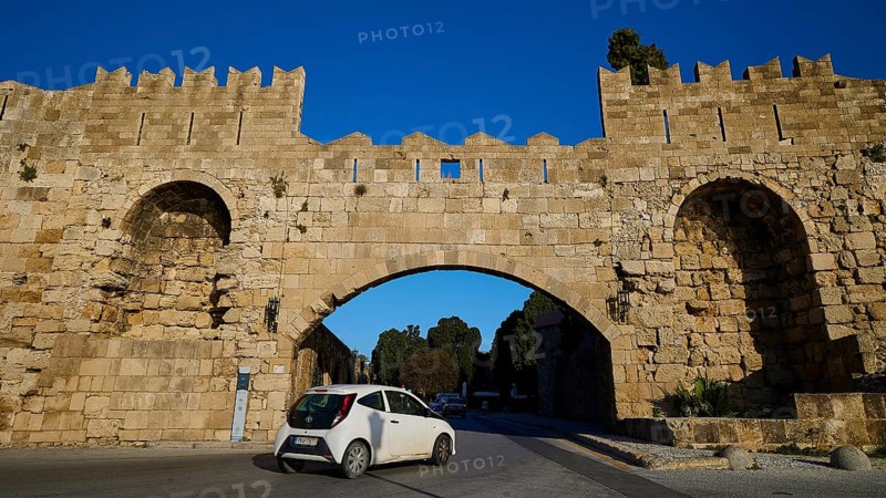 Arsenal Tor, Modern car drives through a historic stone gate on the road, harbour area, Rhodes Town, Rhodes, Dodecanese, Greek Islands, Greece