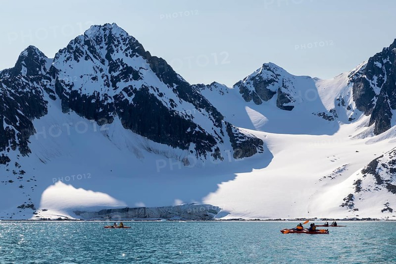Group of canoeists Glacier and mountain range with snow, sea, Fugelfjorden, Spitsbergen, Svalbard