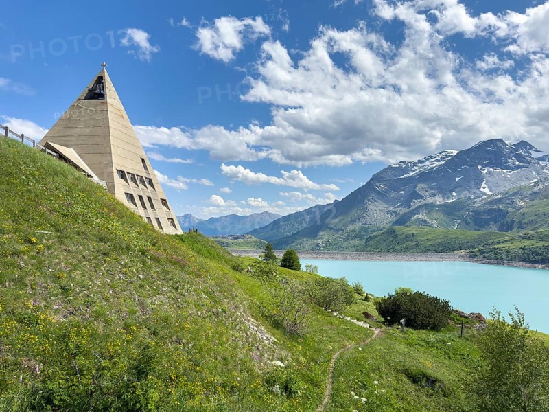 View of left Museum Musée du Mont Cenis on pass road to pass Alpine pass mountain pass Col du Mont Cenis Colle del Moncenisio, right reservoir Lac du Mont Cenis with Barrage dam wall in the background, Mont Cenis massif, Massif du Mont-Cenis, Graian Alps, Lanslebourg, Rhone-Alpes, France