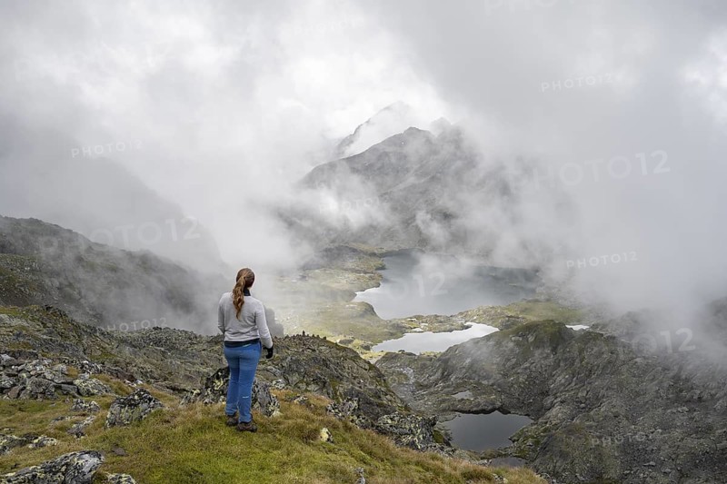 Mountaineer in front of mountain lakes Wangenitzsee and Kreuzsee, cloudy mountain peaks in the morning, Schober group, Hohe Tauern National Park, Carinthia, Austria
