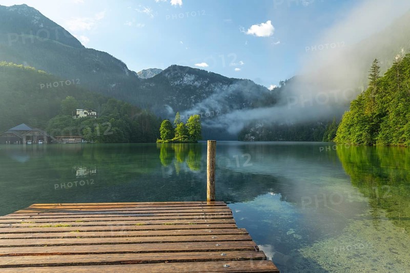 Mystical morning at Königssee in Schönau with boathouses and Christlieger. Sunrise and beautiful wafts of mist over the Königssee in the basin