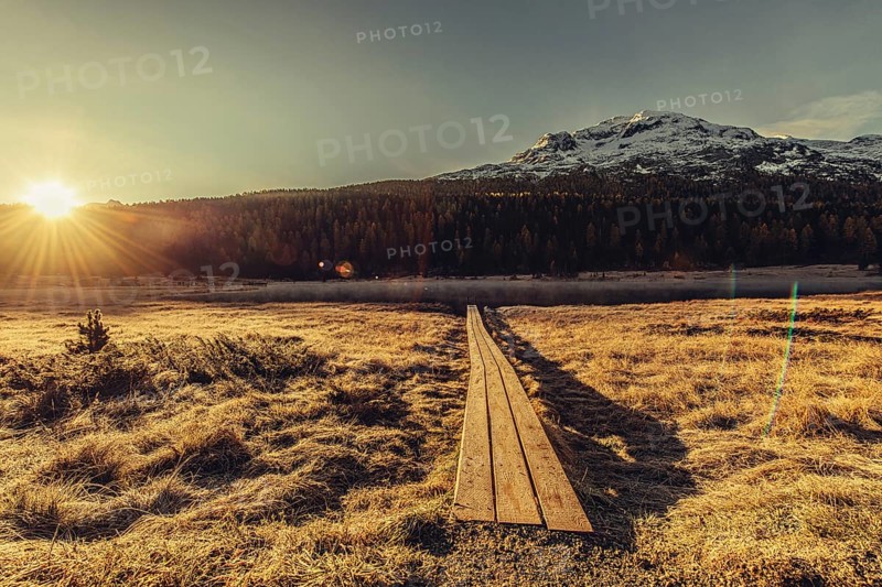 Lake Staz near Sankt Moritz in the Engadin in Switzerland. Morning atmosphere with fog in autumn. Water reflection and snow-covered mountains in the background
