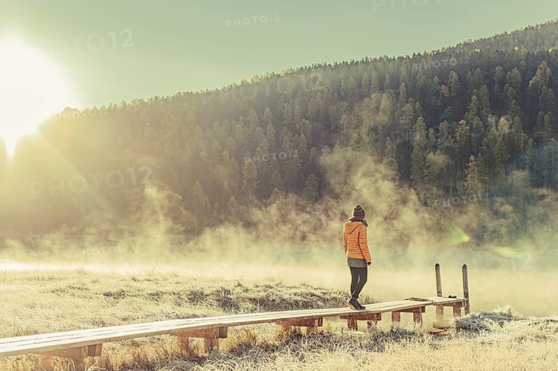 Young woman at Lake Staz near Sankt Moritz in the Engadine in Switzerland. Morning atmosphere with fog in autumn. Reflection of water