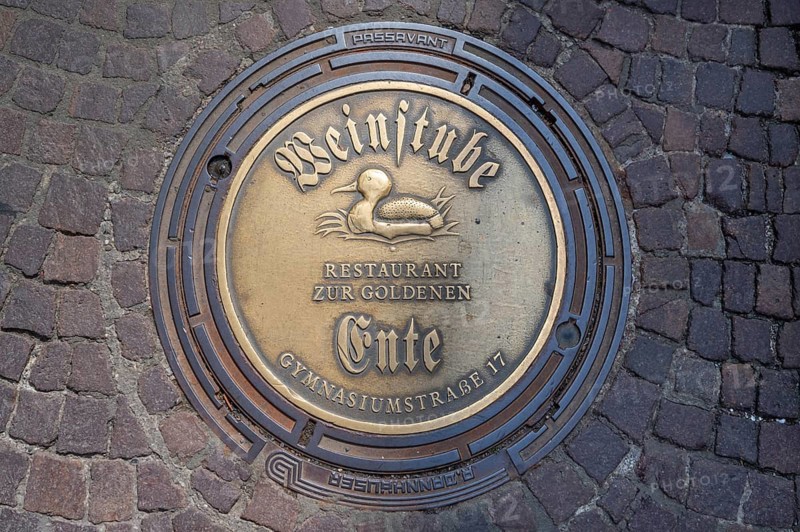 Municipal manhole cover with an advert for a wine bar, Biberach an der Riß, Baden-Württemberg, Germany