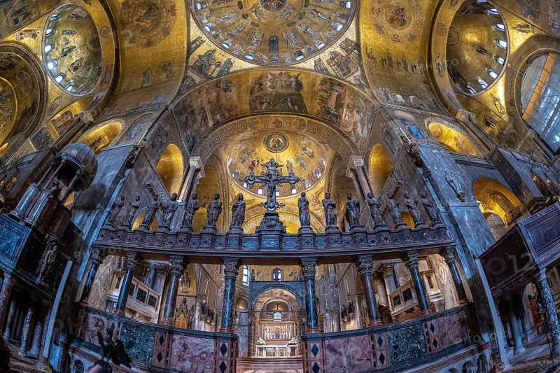 Wide angle view of the richly decorated interior of saint mark's basilica, highlighting the intricate frescoes, golden mosaics, and religious sculptures