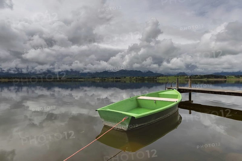 Storm clouds at sunset, a green rowing boat lashed to the wooden jetty, Hopfensee, Hopfen am See, near Füssen, Ostallgäu, Allgäu, Bavaria, Germany