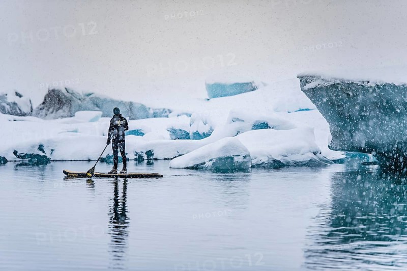 Man stand up paddling, snowfall, glacier lagoon Jökulsarlon at Vatnajökull, Iceland* Man stand up paddling on glacier lagoon Jokulsarlon at Vatnajokul, snowfall, Iceland