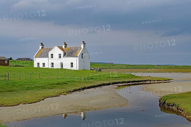 Lonely white house in a green field under a cloudy sky, Isle of Harris, Hebrides, Scotland, United Kingdom