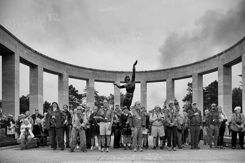 Funeral service, mourning relatives pause during the playing of the US national anthem, bronze statue The Spirit of American Youth Rising from the Waves by Donald De Lue, military cemetery, Normandy American Cemetery and Memorial, Omaha Beach, D-Day, Operation Overlord, Saint-Laurent-sur-Mer near Colleville-sur-Mer, black and white, Normandy, Calvados, France