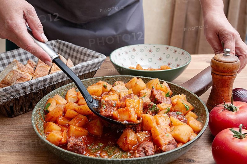 Homemade stew with potatoes and meat, cooked in a frying pan, is served on a plate