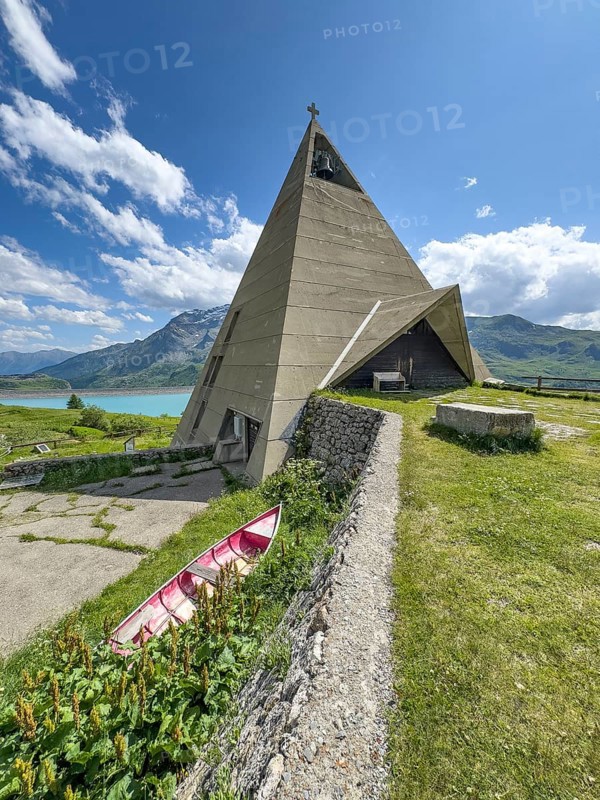 Mont-Cenis Pyramid Museum built in 1967 above the Lac du Mont Cenis in a stylised pyramid as a museum to commemorate the Egyptian campaigns of Emperor Napoleon Bonaparte and the time in front of the construction of the reservoir, old rowing boat in the lower left foreground, Mont Cenis massif, Massif du Mont-Cenis, Graian Alps, Lanslebourg, Rhone-Alpes, France