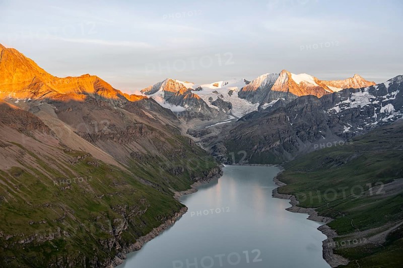 View at the summit of Mont de la Blana, alpenglow at sunset, view of a blue mountain lake, Lac des Dix reservoir, behind mountain peak Mont Blanc de Cheilon with glacier, Hérménence, Valais Alps, Valais, Switzerland
