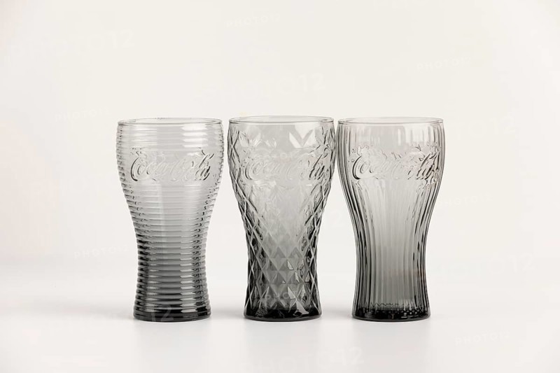 Three stylish, differently designed cola glasses in transparent and black tones