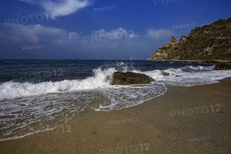 Sea crashing against rocks on the beach under a clear blue sky, Ricadi, Capo Vaticano