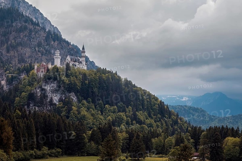 The impressive Neuschwanstein Castle on a wooded mountain under a fascinating cloudy sky, Schwangau, Bavaria