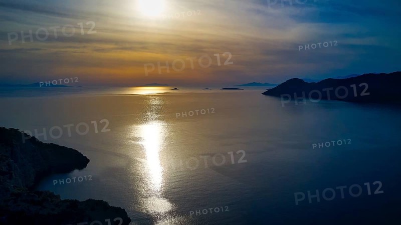 Drone shot, Fascinating sunset with light reflection in the water, Holy Week, Bay of Panormitis, Panormitis Monastery, Symi, Dodecanese, Greek Islands, Greece