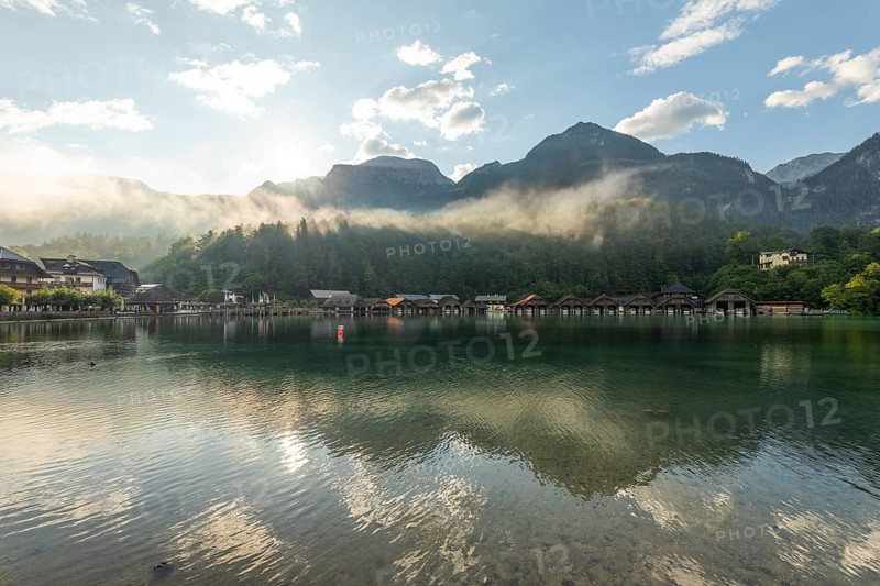 Mystical morning at Königssee in Schönau with boathouses. Sunrise and beautiful wafts of mist over the Königssee in the basin