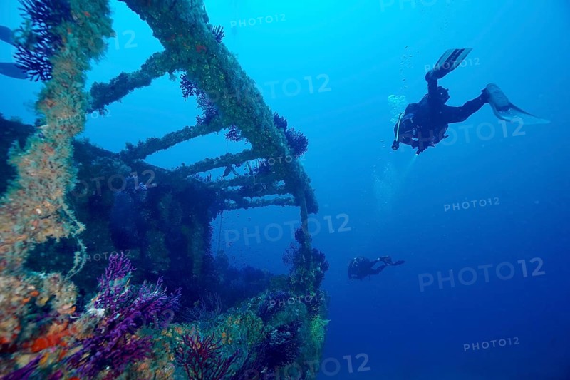 Divers explore a shipwreck in deep, clear water. Dive site wreck Le Grecq, Giens peninsula, Mediterranean Sea, Provence Alpes Côte d'Azur, France