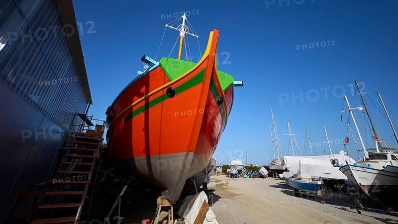 Frontal view of a ship's bow in orange and green on a shipyard site, Diakofti boatyard, new construction of a coloured wooden boat, Diakofti, Patmos, Dodecanese, Greek Islands, Greece
