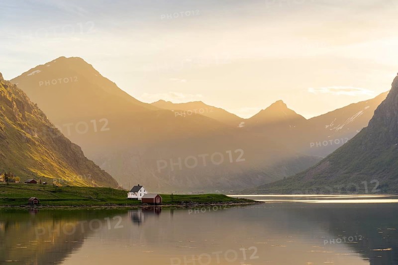 Landscape with sea and mountains on the Lofoten Islands. The fjord Flakstadpollen and some houses belonging to the village of Flakstad. At night during the midnight sun. Flakstadoya, Lofoten, Norway