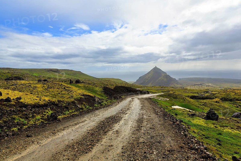 Gravel track through barren moss-covered volcanic landscape, cone-shaped mountain Stapafell, rain clouds, changeable weather, Arnarstapi, Snaefellsjökull volcanic system, Snaefellsnes peninsula, West Iceland, Iceland