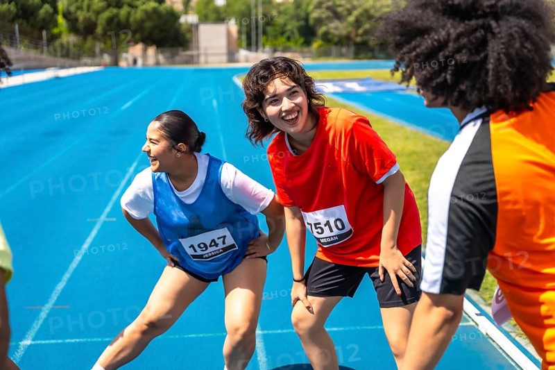 Runners stretching their legs on a vibrant blue track, recovering after a race, embodying teamwork and the spirit of fitness