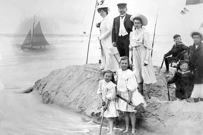 Family on the beach, 1910s, Victorian beach shot of a family with children next to a sailing boat in the background, historical photo