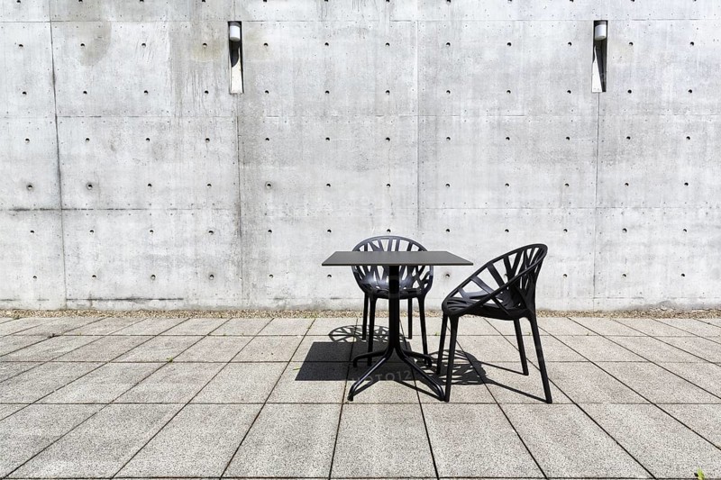 Black table and two plastic chairs in the courtyard made of exposed concrete, architect Tadao Ando, design, conference pavilion, conference building, Vitra Campus, Vitra Design Museum, Weil am Rhein, Baden-Württemberg, Germany