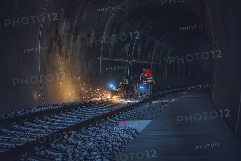 A worker in an orange waistcoat works on the rails in a dark tunnel while sparks fly, grinding work on the Hermann Hesse railway, Ostelsheim, district of Calw, Germany