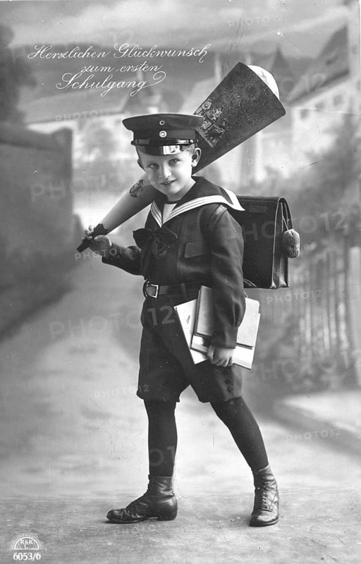 School enrolment, 1920s, A boy in school uniform with school bag and cone in a studio, Historical photo