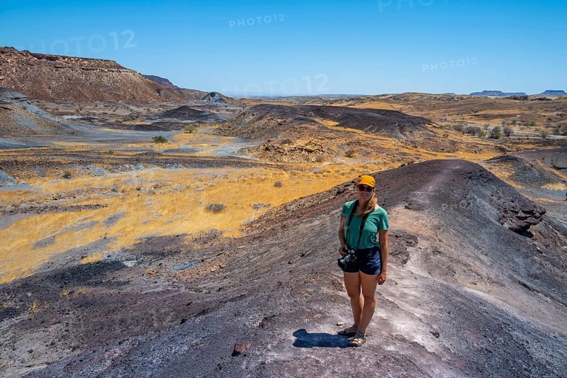 Tourist, Dry landscape with yellow grass and black volcanic hills, Burnt Mountain, Damaraland, Kunene, Namibia