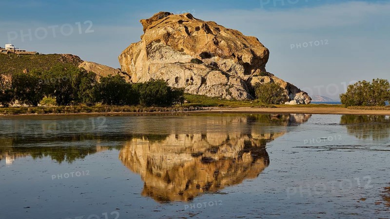 Large rock formation calmly reflected on the surface of the water, surrounded by nature, Kalikatsou Rocks, Seasonal Salt Lake, Grikos, Patmos, Dodecanese, Greek Islands, Greece