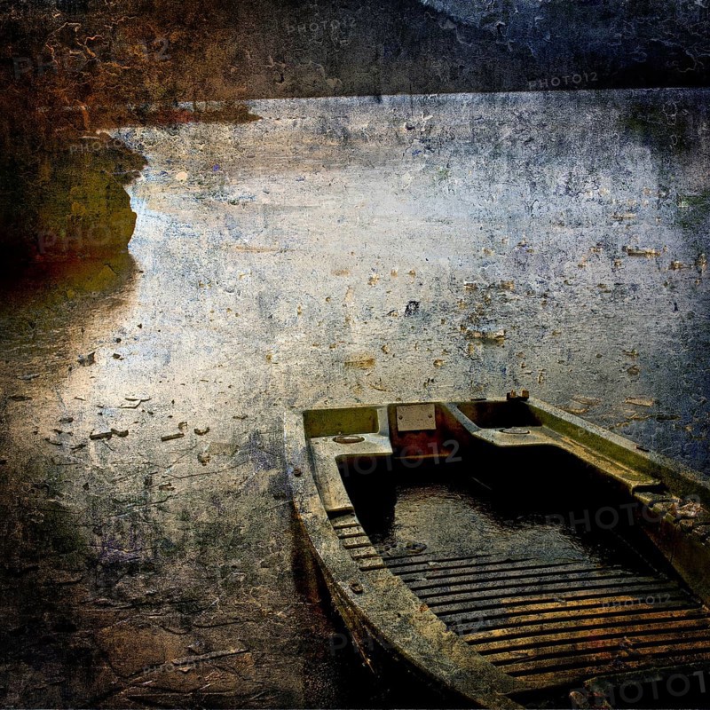 A weathered boat lies still on a serene water body at dusk, with reflections of light dancing on its surface and uneven shorelines adding to its rustic charm. Puy de Dome. Auvergne-Rhone-Alpes. France