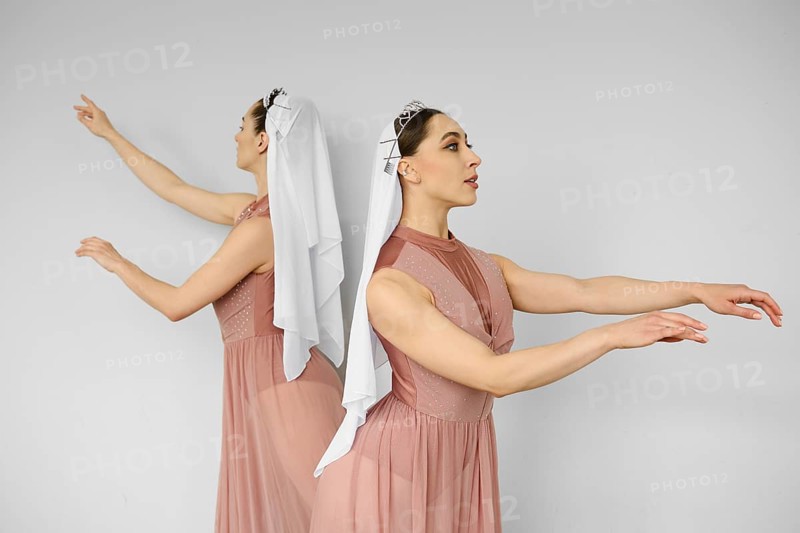 Two ballerinas standing back to back and waving hands on grey background