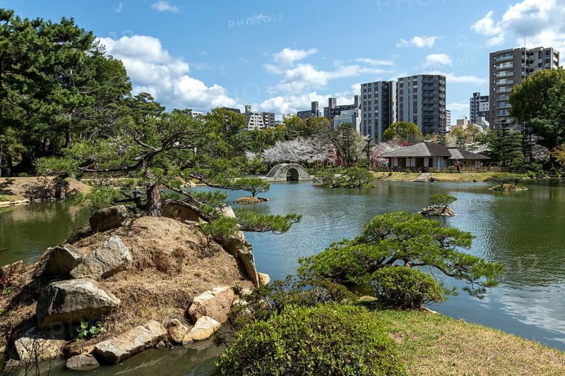 Shukkei-en with Sekisui-gan stone formation, green plants, trees and Koko-kyo stone bridge over Takuei-chi pond in spring, historical Japanese strolling garden, Japanese garden, green area, tourist attraction, sight, Naka-ku, Hiroshima, Japan