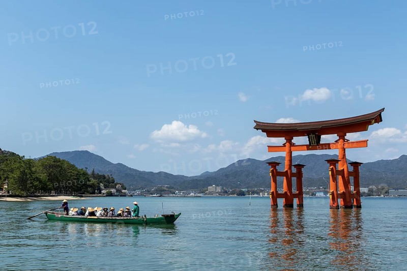An excursion boat with tourists passes through the torii in the water, sight, tourist attraction, UNESCO World Heritage Site, Itsukushima Shrine, Miyajima Island, Hatsukaichi, Hiroshima Prefecture, Japan