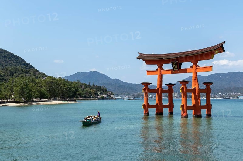 An excursion boat with tourists passes through the torii in the water, sight, tourist attraction, UNESCO World Heritage Site, Itsukushima Shrine, Miyajima Island, Hatsukaichi, Hiroshima Prefecture, Japan