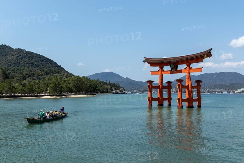 An excursion boat with tourists passes through the torii in the water, sight, tourist attraction, UNESCO World Heritage Site, Itsukushima Shrine, Miyajima Island, Hatsukaichi, Hiroshima Prefecture, Japan