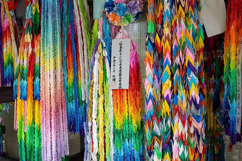 Chains of colourful origami cranes made of paper as a sign of peace in the Peace Park, landmark, UNESCO World Heritage Site, peace monument and memorial to the victims of the atomic bombing of Hiroshima, Naka Ward, Hiroshima, Japan