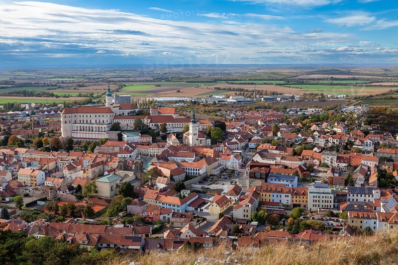 Panoramic view of a town with a historic castle and churches, surrounded by fields and clouds, Mikulov Nikolsburg Czech Republic
