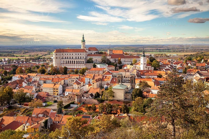 Panorama of a historic town with castle and churches, surrounded by autumn trees and a wide sky, Mikulov Nikolsburg Czech Republic