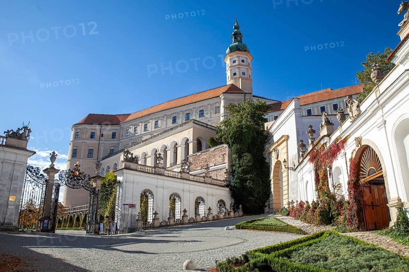 A magnificent castle with a richly decorated entrance gate, surrounded by trees under a blue sky, Mikulov Nikolsburg Czech Republic